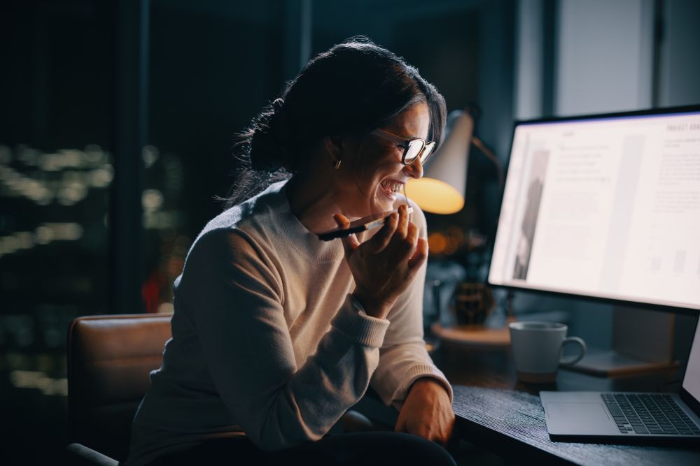 Late night work calls: Happy business woman working with technology in her home office